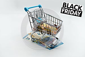 Shopping cart with Black Friday sign and Euro coins and banknotes.