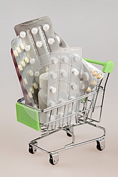 Shopping cart with blisters of tablets and pills concept of self-treatment and purchase of medicines