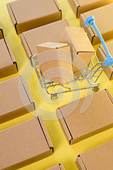 Shopping cart with boxes on a yellow background. The concept of sales, discounts, online shopping and delivery