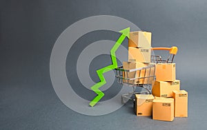 Shopping cart with cardboard boxes and a green up arrow. Increase the pace of sales and production of goods.