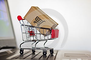 Shopping cart with Carton on computer keyboard. Online shopping, e-commerce and worldwide shipping concept