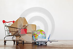 Shopping cart with cartons, airplane and earth globe. Global logistics, shipping and worldwide delivery business concept