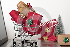 Shopping cart with christmas gifts on laptop computer. Online shopping, e-commerce and worldwide shipping concept