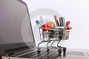 Shopping cart with cosmetics is on the laptop. Online sales concept