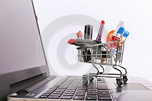 Shopping cart with cosmetics is on the laptop. Online sales concept