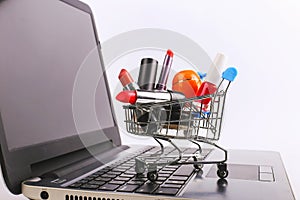 Shopping cart with cosmetics is on the laptop. Online sales concept