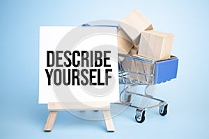 Shopping cart and easel with a DESCRIBE YOURSELF sign. Sale concept