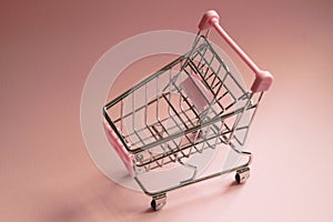 Shopping cart. Empty Supermarket trolley on pink background. Consumerism concept photo.