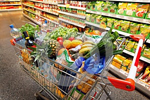 Shopping cart with fruit in supermarket