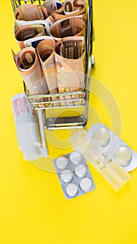 shopping cart full of medicine with pills and capsules and euro banknotes. money . drug cost concept