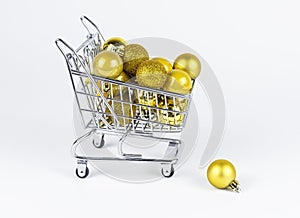Shopping cart full of Christmas baubles, fallen ball near trolley. New Year consumerism concept