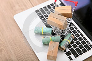 A shopping cart full of express parcels and a rolled Australian dollar bill next to it are placed on the laptop keyboard