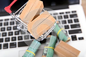 A shopping cart full of express parcels and a rolled Australian dollar bill next to it are placed on the laptop keyboard