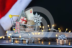 Shopping cart full of gift boxes and Christmas tree on keyboard of laptop computer. Concept online shopping and holiday sale