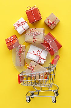 Shopping cart full of gift boxes on yellow background