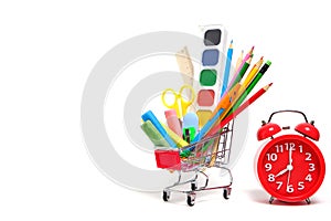 Shopping cart full school supplies and office supplies and red alarm clock white background