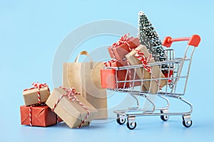 Shopping cart full of various gift boxes and a Christmas tree