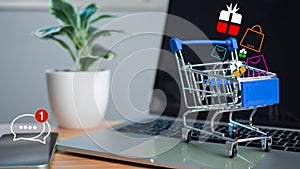 Shopping cart and gift box icons placed on laptop computer represent online shopping concept, website, e-commerce, market