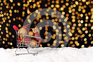 Shopping cart and gifts on beautiful background with snow and lights. Front view. Christmas, new year concept. Copy