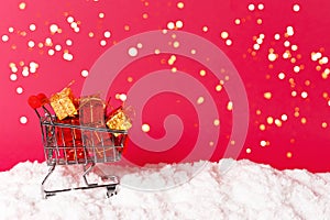 Shopping cart and gifts on beautiful background with snow and lights. Front view. Christmas, new year concept. Copy
