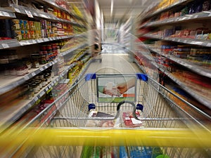 Shopping cart between goods shelves of a supermarket