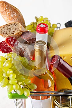 Shopping cart with groceries. Salami, grapes, bread, cheese and wine