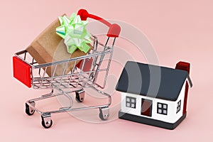 Shopping cart and house on beige background. Real estate sale or purchase concept