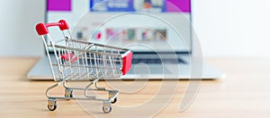 Shopping cart and laptop computer with marketplace website. business, technology, ecommerce, digital banking and online payment