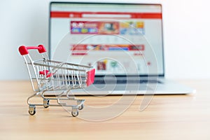 Shopping cart and laptop computer with marketplace website. business, technology, ecommerce, digital banking and online payment