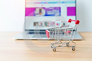 Shopping cart and laptop computer with marketplace website. business, technology, ecommerce, digital banking and online payment