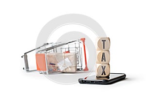 Shopping cart laying on the side and cubes with the word TAX on a smartphone