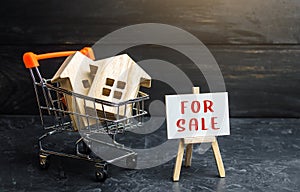 Shopping cart loaded with houses and sign for sale. Buying and selling housing. Saving money in real estate, investing in housing