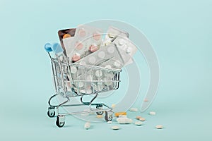 Shopping cart loaded with pills on a blue background. The concept of medicine and the sale of drugs. Copy space