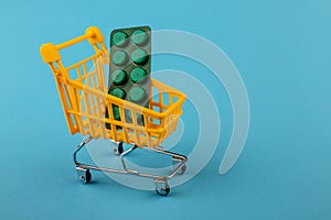 Shopping cart loaded with pills drugs or medicine on yellow background.antibiotics. Women's health, medicine and