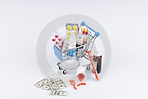 Shopping cart with medicines and moneys on white background