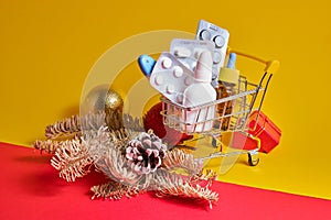 Shopping cart with medicines on yellow-red background, buying medicines before christmas and new year, cold and flu season