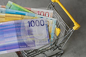 Shopping cart with Norwegian money, Concept, rising prices, Inflation in stores, Norway Kroner, all banknotes