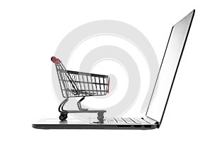 Shopping cart over laptop isolated on white background. E-commerce, business concept