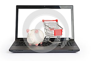 Shopping cart and piggy bank on laptop