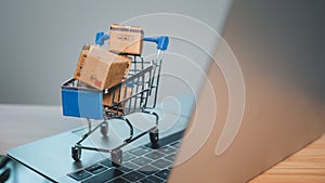 Shopping cart and product boxes placed on laptop computer represent online shopping concept, website, e-commerce, marketplace