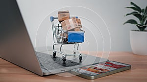 Shopping cart and product boxes placed on laptop computer represent online shopping concept, website, e-commerce, marketplace