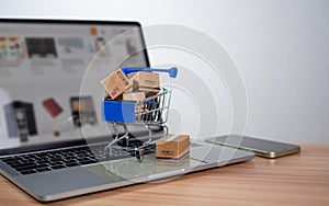 Shopping cart and product boxes placed on laptop computer represent online shopping concept, website, e-commerce, marketplace
