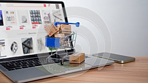 Shopping cart and product boxes placed on laptop computer represent online shopping concept, website, e-commerce, marketplace