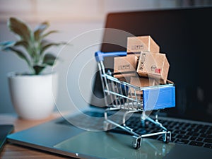 Shopping cart and product boxes placed on laptop computer represent online shopping concept, website, e-commerce, marketplace