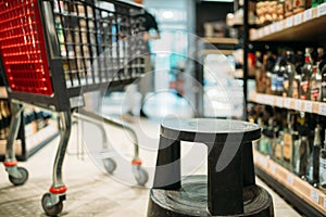 Shopping cart between shelves with alcohol drinks