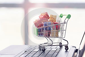 Shopping cart, small boxes and laptop. Online shopping concept.