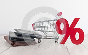 Shopping cart from the supermarket and sign percent with leather wallet on white wood background. Shopping in the Mall, shop,