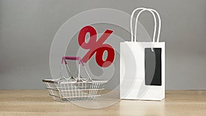 Shopping cart from the supermarket with sign percent on wood table background. Shopping in the Mall, shop, shopping, a large