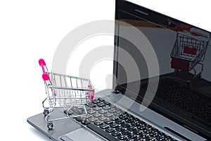 Shopping cart or supermarket trolley with laptop notebook isolated on white background, e-commerce and online shopping concept.