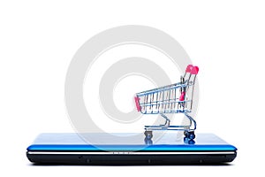 Shopping cart or supermarket trolley with laptop notebook isolated on white background, e-commerce and online shopping concept